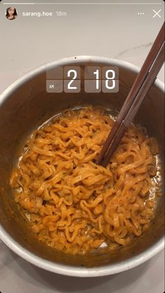 a bowl filled with noodles and chopsticks on top of a table