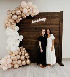 two women standing next to each other in front of balloons