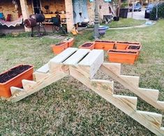 several wooden planters sitting on top of grass in front of a house with stairs leading up to them