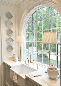 a kitchen with an arched window, sink and lamp in front of the countertop