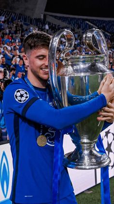 a soccer player holding up a trophy in front of a crowd