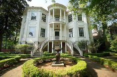 a large white house with a fountain in the front yard