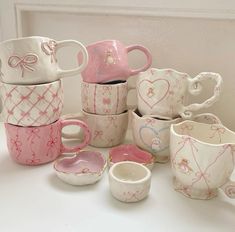 there are many cups and saucers that have hearts painted on them, all in different colors