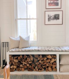 a bench made out of firewood in front of a window