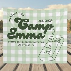 the welcome sign for camp emma is displayed on a picnic table next to water