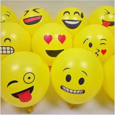 many yellow balloons with faces painted on them are arranged in a row and one has a red heart