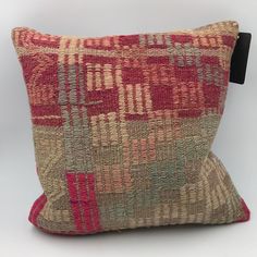 a red and beige pillow on a white background with a black tag in the corner