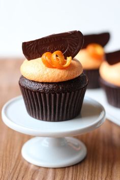 there is a cupcake with chocolate icing and an orange peel on top, sitting on a white plate