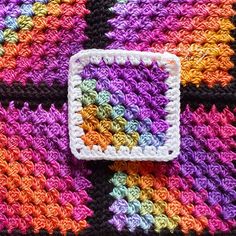 a crocheted square is sitting on top of a blanket