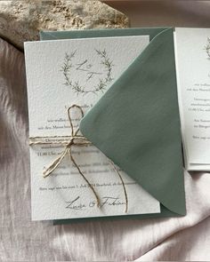 the wedding stationery is laid out on top of the bed with two envelopes