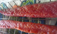 two sausages cooking on a wire rack in the oven, one is red and the other is brown