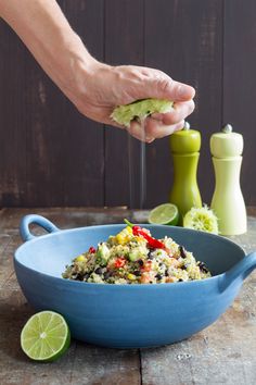 a person is scooping food out of a blue bowl with limes on the side