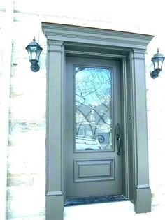 the front door is painted gray and has two lights on either side, along with a window