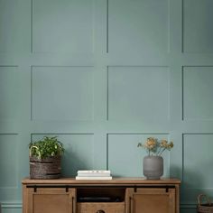 a wooden table with two baskets on it and a plant in the corner next to it