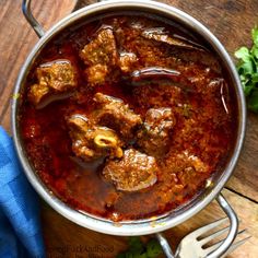 a pot filled with meat and sauce on top of a wooden table