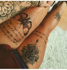 two women with tattoos on their legs sitting next to each other and holding cell phones