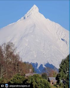 a large snow covered mountain in the distance with trees and houses on it's sides