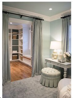 a bedroom with blue walls and white furniture in the corner, along with an open closet