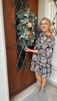 a woman standing in front of a door holding a wreath