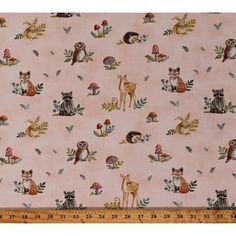 a pink fabric with woodland animals and mushrooms on the ground, in front of a ruler