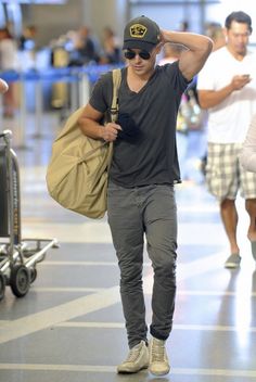 a man walking through an airport with his hand on his head and other people in the background