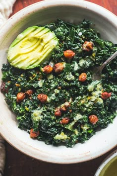 a bowl filled with spinach and avocado on top of a wooden table