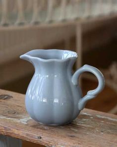 a white pitcher sitting on top of a wooden table