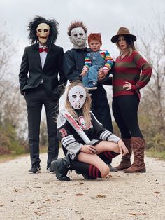 a group of people in costumes posing for a photo on a dirt road with trees and bushes behind them