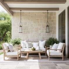 an outdoor patio with white cushions and wooden furniture