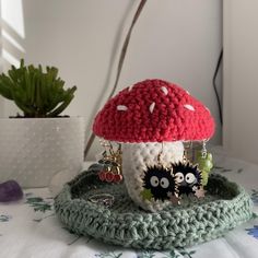 a crocheted mushroom is sitting on a table with earrings hanging from it's sides