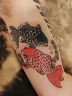 a fish and goldfish tattoo on the arm