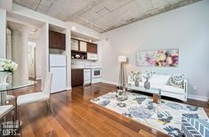 a living room filled with furniture next to a kitchen and dining room table on top of a hard wood floor