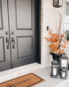 two lanterns are sitting on the front porch next to a welcome mat that says welcome