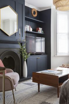 a living room with dark blue walls, white and pink furniture and a large mirror on the wall