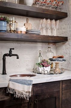 a kitchen counter with wine glasses, dishes and other items on it's shelves