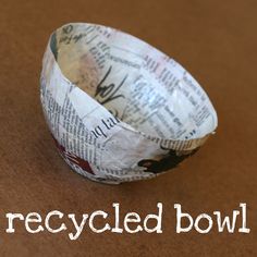 a paper bowl sitting on top of a brown table next to a sign that says recyclied bowls