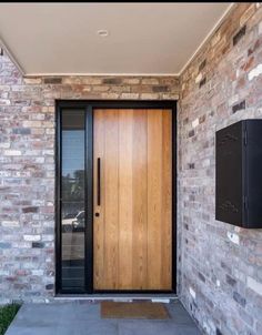 a modern wooden door in front of a brick wall with a flat screen tv mounted on it's side