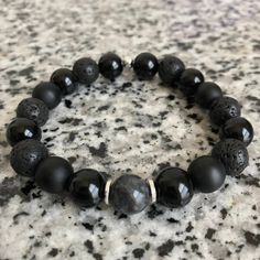 Lava Stone, Matte Black Onyx, And Onyx 10mm Bracelet w/ Silver Accents Mixed, matched, and designed with a variety of elegant beads for a graceful look. This is a beautiful piece made to be worn separately or combined with our other Embody'd Art pieces! This bracelet can also be worn as an oil diffuser. Just add one drop of your favorite oil to the AAA grade lava beads and you're set to go. This bracelet is crafted with quality elastic stretch cord. This bracelet is also designed to fit snug on