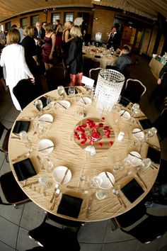 a group of people standing around a wooden table with plates and glasses on top of it