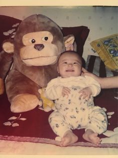 a baby sitting next to a large stuffed monkey