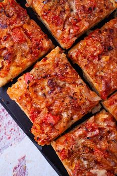 several square slices of pizza sitting on top of a pan covered in cheese and tomato sauce