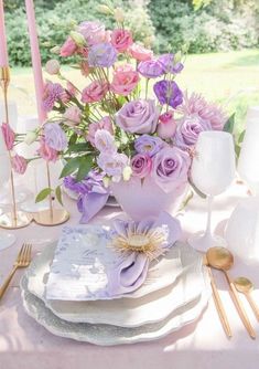 the table is set with pink and purple flowers