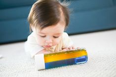 a small child laying on the floor playing with a toy block that is shaped like a rectangle