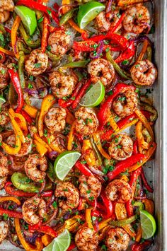 shrimp and peppers in a baking pan with lime wedges