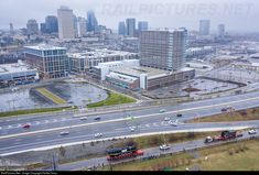 an aerial view of a city with lots of traffic on the road and buildings in the background