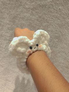 a hand is holding a small crocheted white object that looks like an elephant