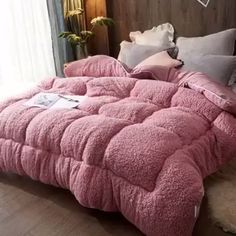 a bed with pink comforter and pillows on top of it in front of a window