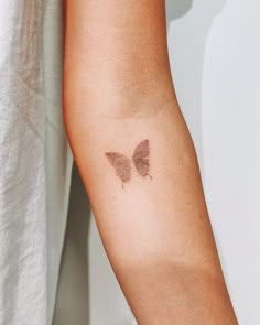 a woman's arm with a butterfly tattoo on the left side of her arm