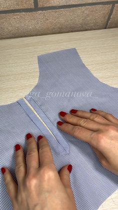 a woman is cutting fabric with scissors on the table