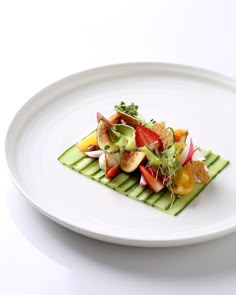 a white plate topped with cucumber, strawberries and radish slices